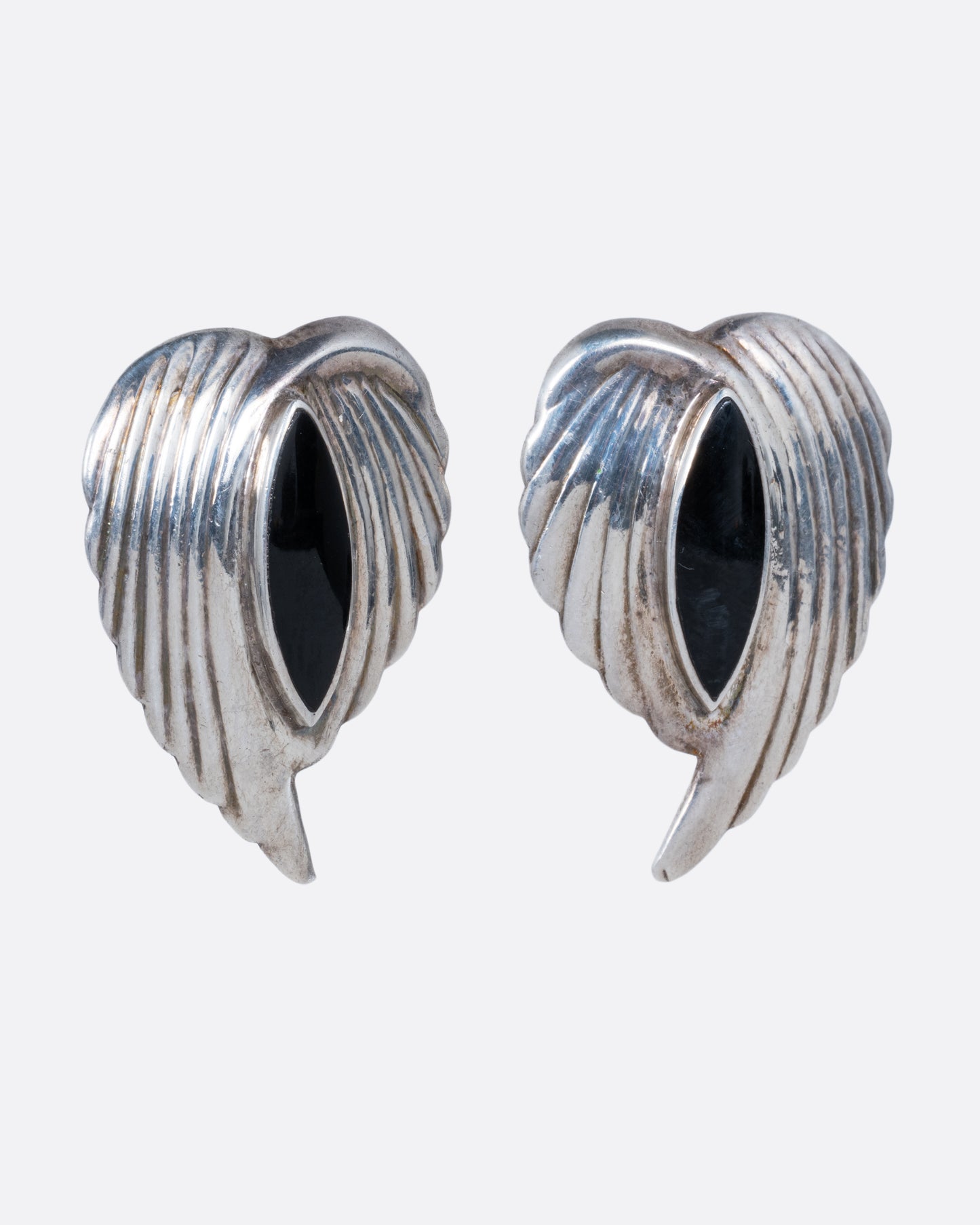 A pair of silver leaf stud earrings with bezel set marquis onyxes at the center. Shown from the side.
