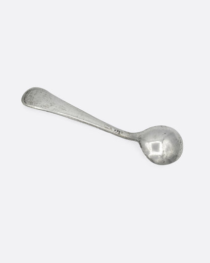 A tiny silver ladle spoon, shown from the back.