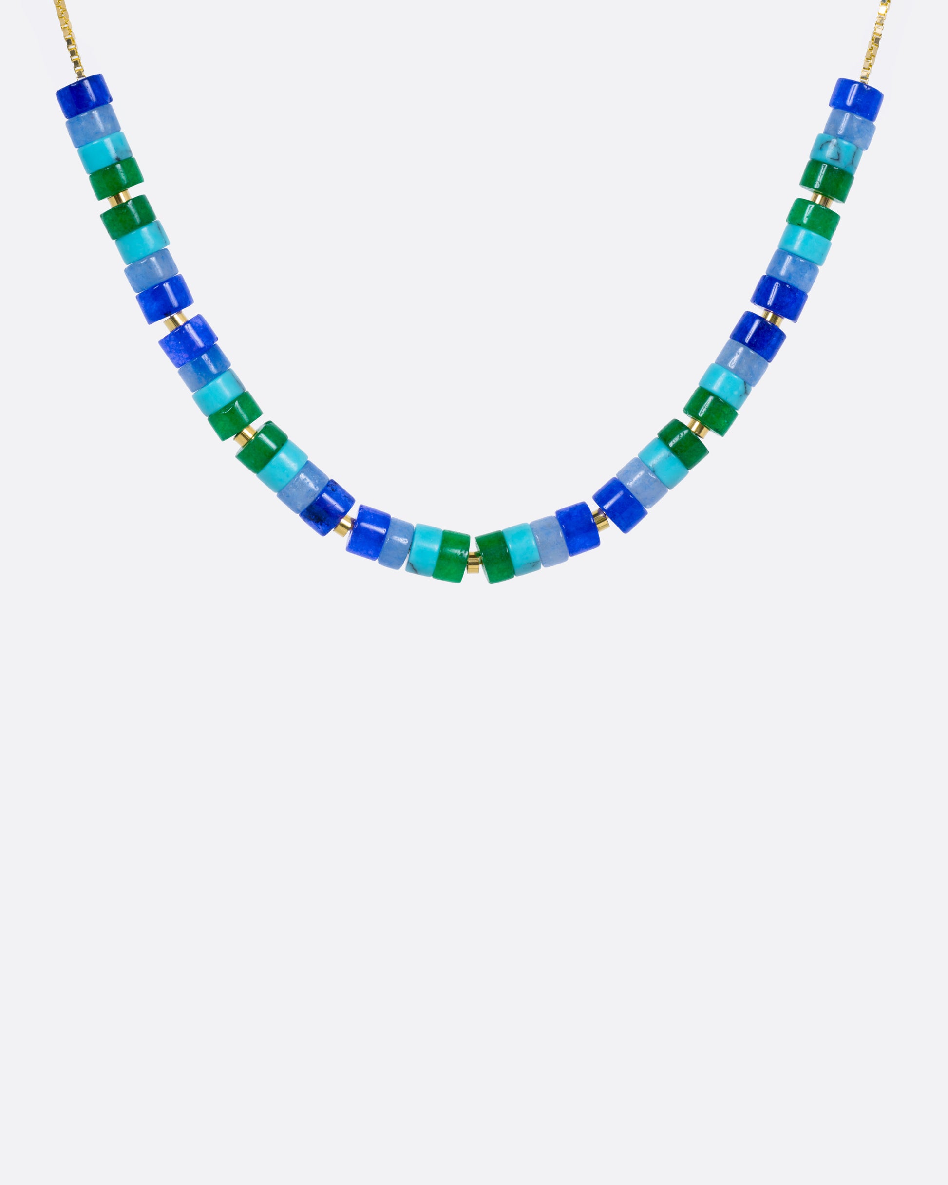 A beaded necklace with mix of gemstones in greens and blues with yellow gold bead accents, shown from the front.