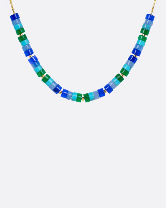 A beaded necklace with mix of gemstones in greens and blues with yellow gold bead accents, shown from the front.