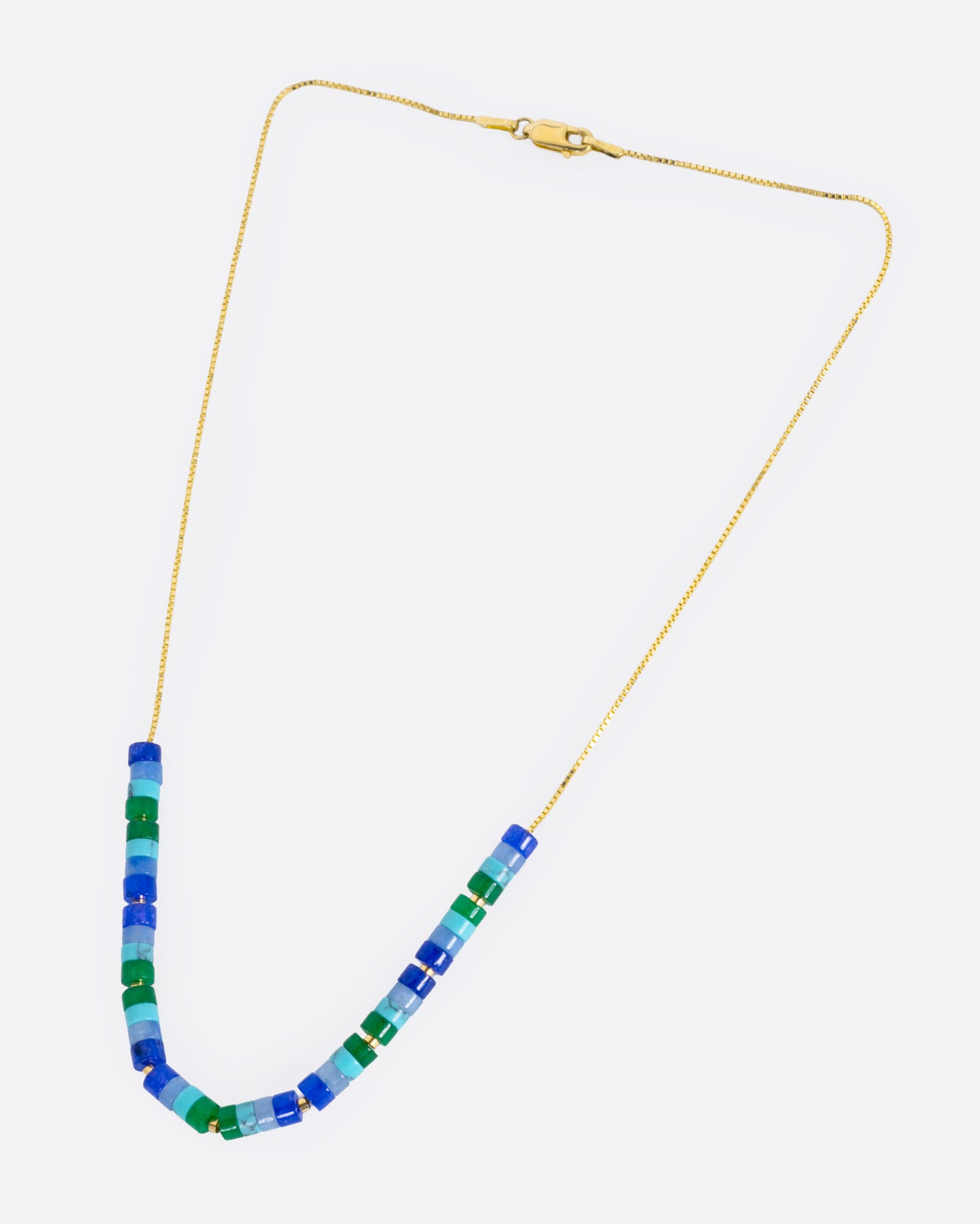 A beaded necklace with mix of gemstones in greens and blues with yellow gold bead accents, shown from the front.