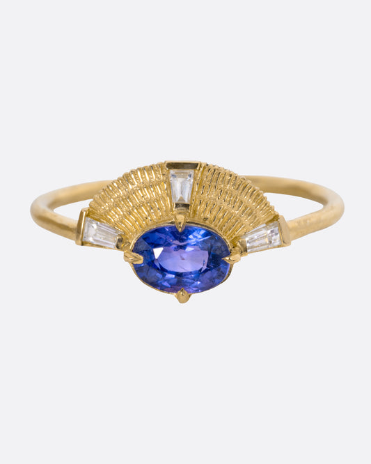 A yellow gold ring with a purple sapphire and three baguette diamonds, shown from the front.