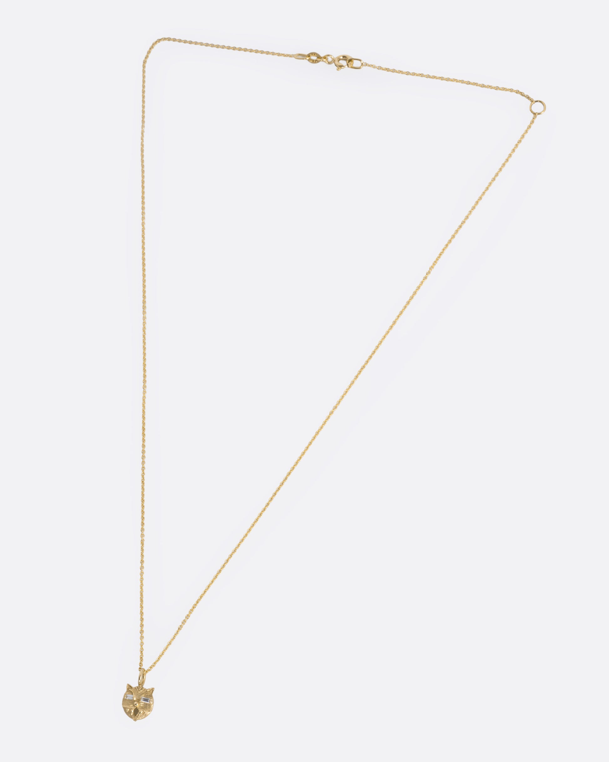 A yellow gold cable chain necklace with a cat head shaped pendant with baguette diamond eyes, shown from the front.