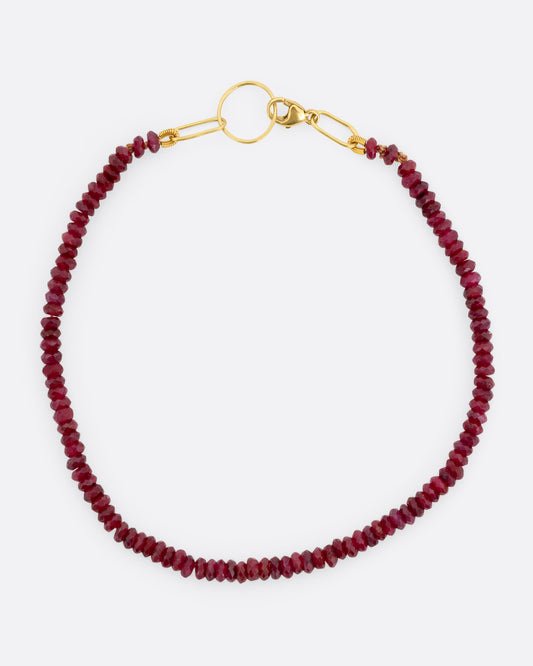 A beaded ruby bracelet with a yellow gold clasp. Shown from the top.