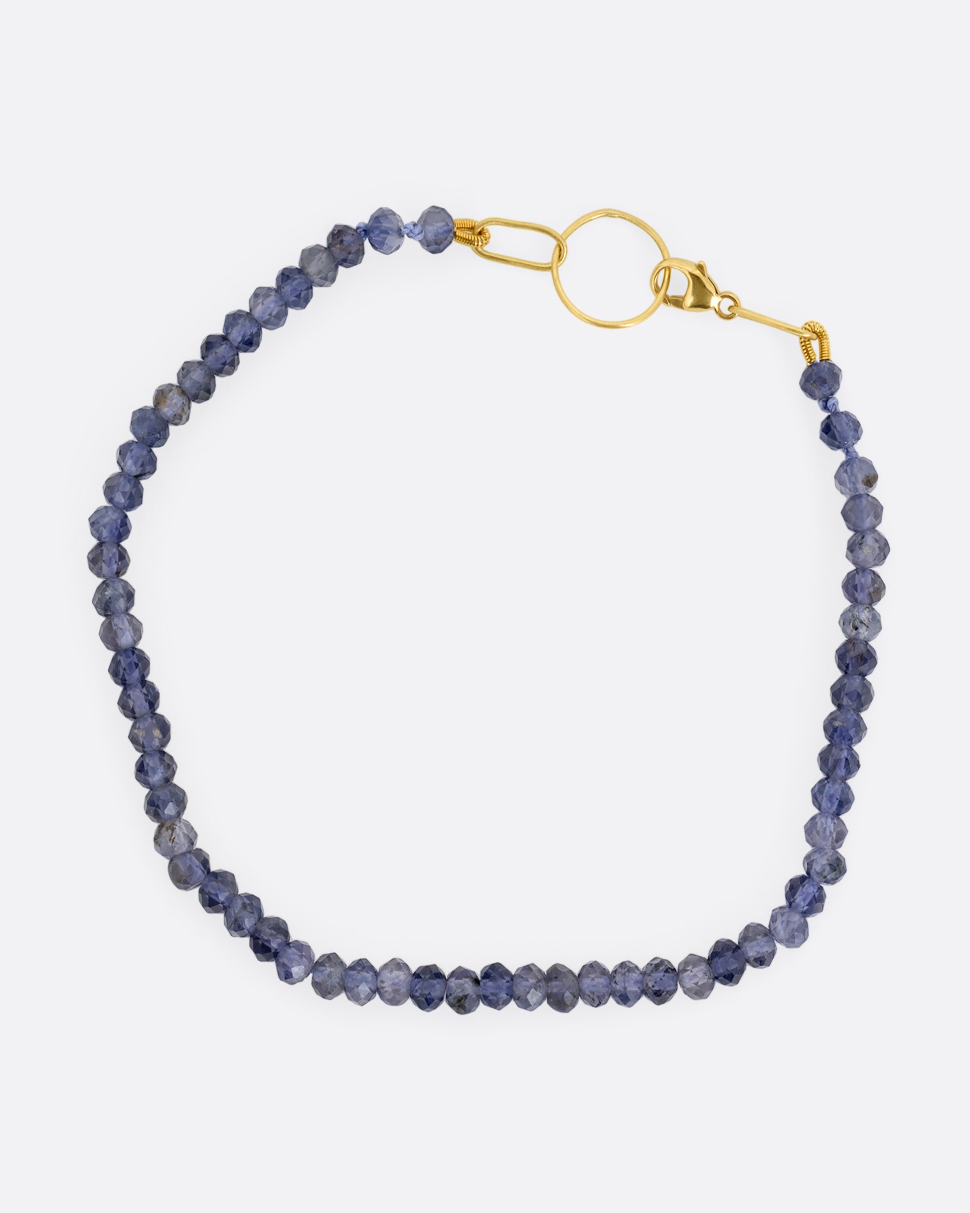 An iolite beaded bracelet with a yellow gold clasp. Shown from the top.