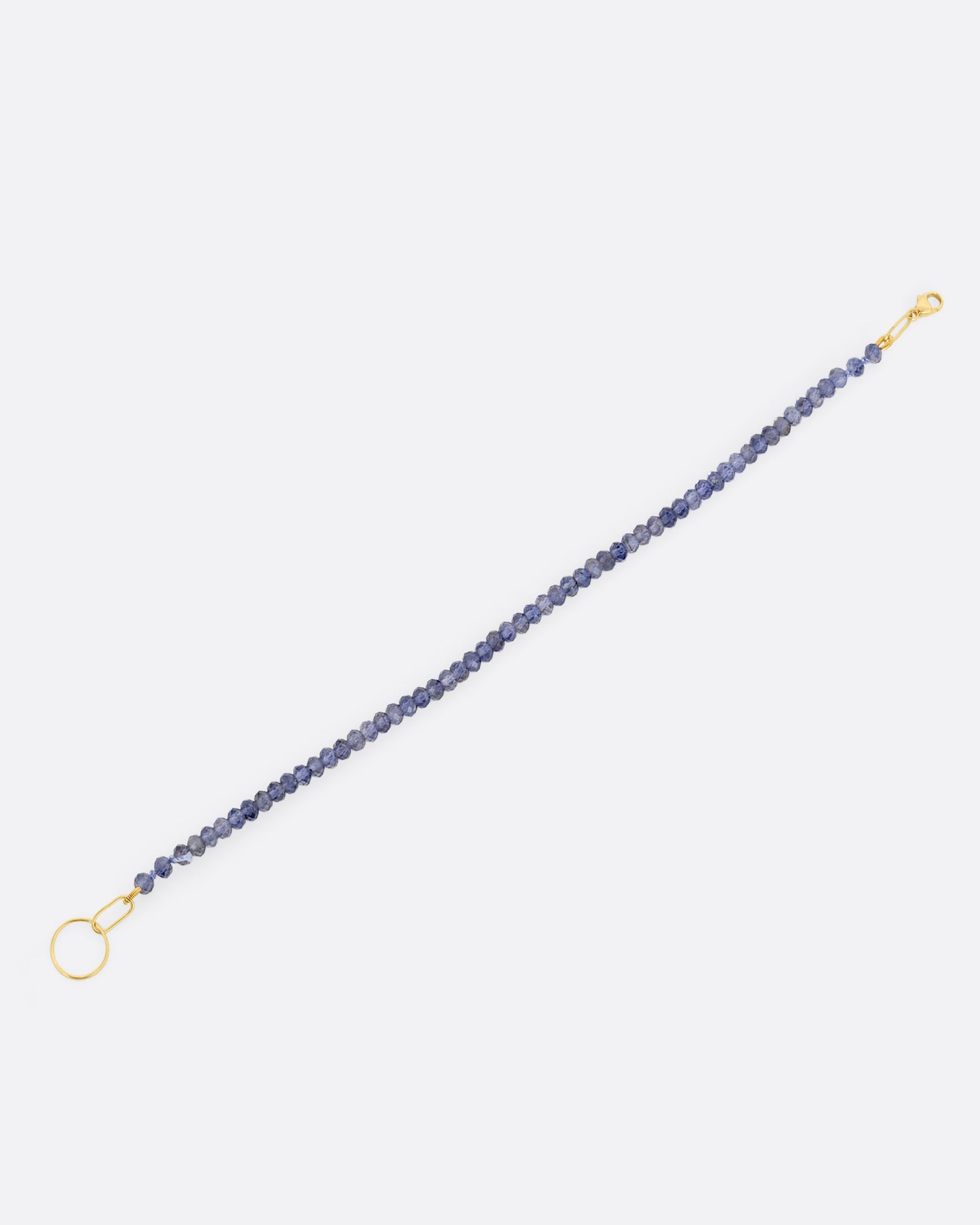 An iolite beaded bracelet with a yellow gold clasp. Shown open lying flat from the side.