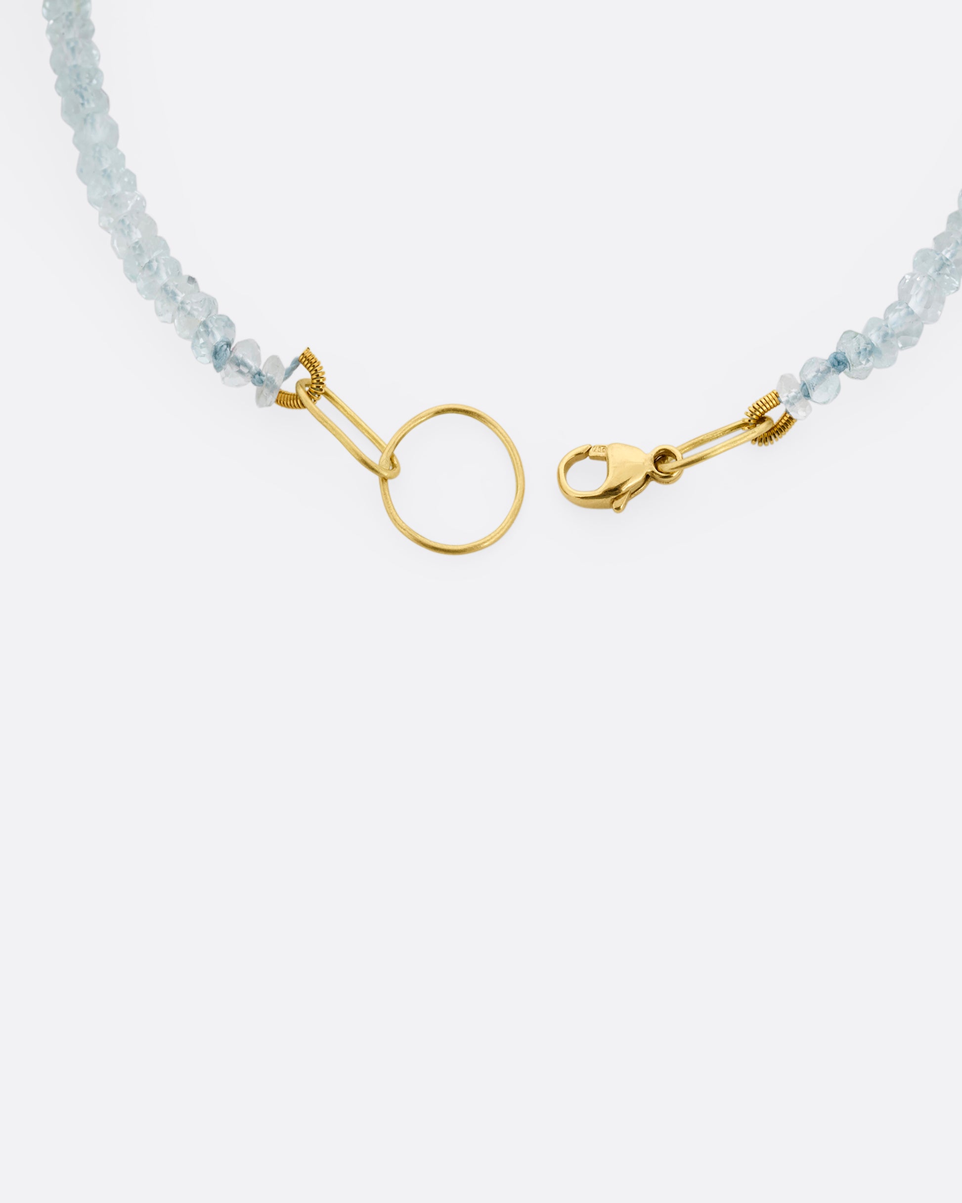 A beaded aquamarine bracelet with a yellow gold clasp. A close up view of the clasp from the top.