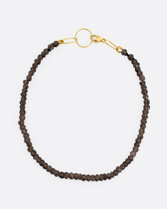 A beaded smoky quartz bracelet with a yellow gold clasp. Shown from the top.