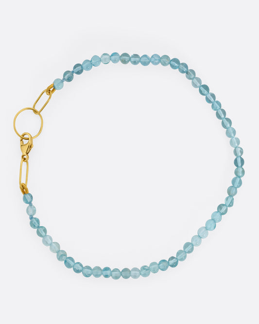  An apatite beaded bracelet with a yellow gold clasp. Shown from the top.