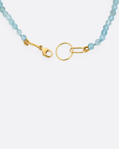A close up of an apatite beaded bracelet with a yellow gold clasp. 