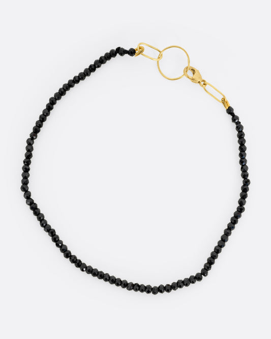  A black spinel beaded bracelet with a yellow gold clasp. Shown from the top.