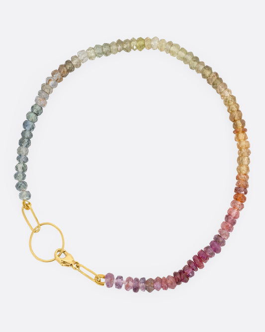 An ombré sapphire beaded bracelet with a yellow gold clasp. Shown from the top.