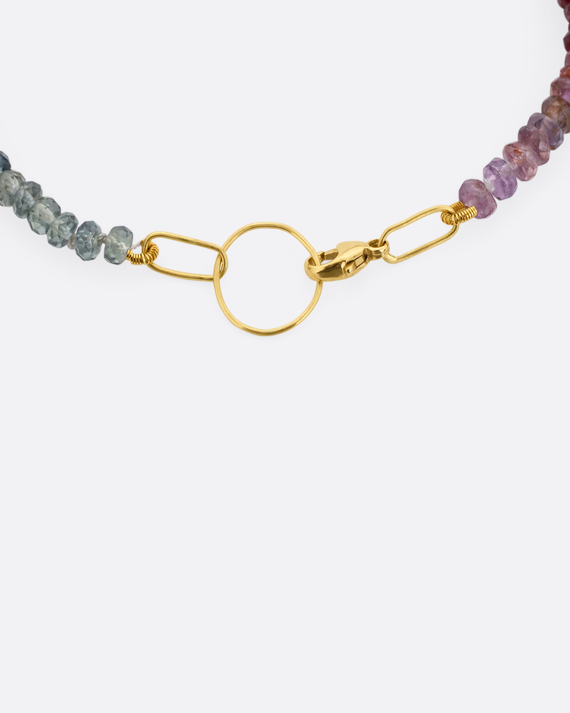 An ombré sapphire beaded bracelet with a yellow gold clasp. A close up view of the clasp shown from the top.