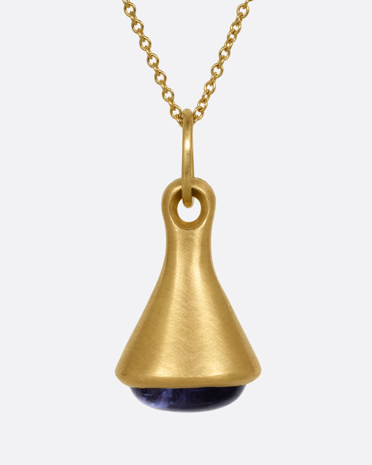 A yellow gold cable chain necklace with a bell shaped pendant with a tanzanite cabochon at the base. Shown from the front.