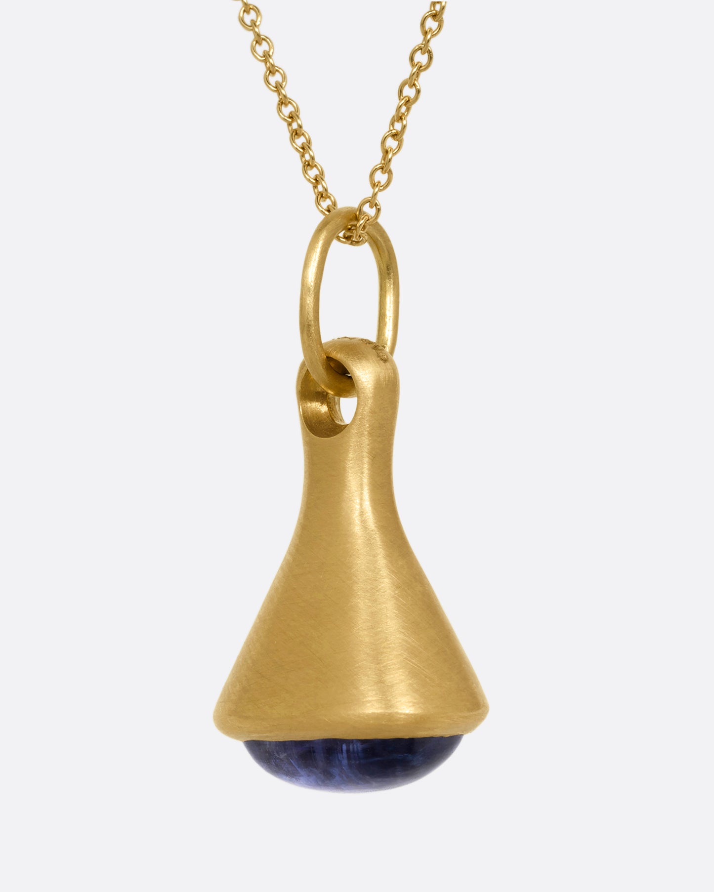 A yellow gold cable chain necklace with a bell shaped pendant with a tanzanite cabochon at the base. Shown from the side.