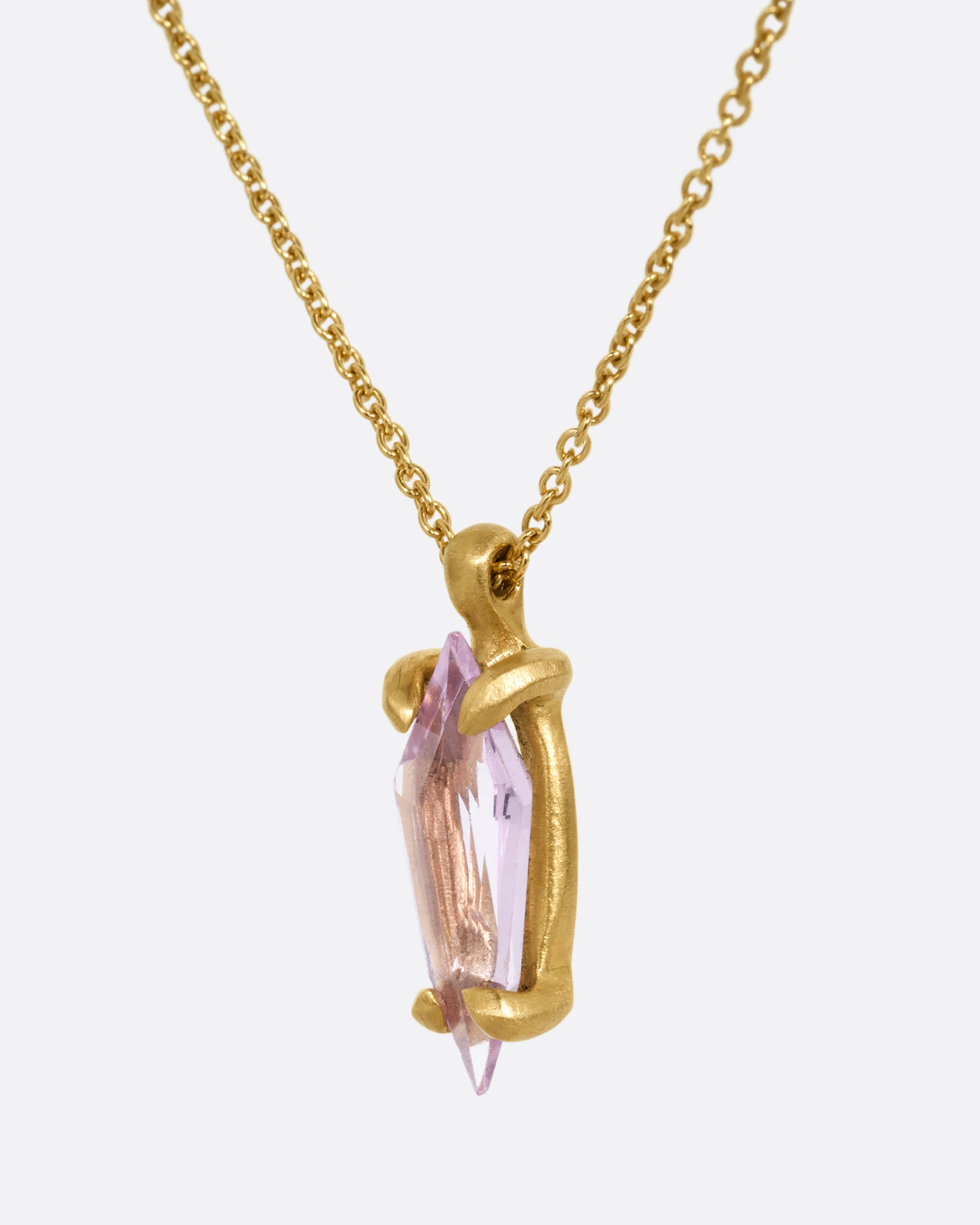 A yellow gold cable chain necklace with a single pink sapphire pendant. Shown from the side.