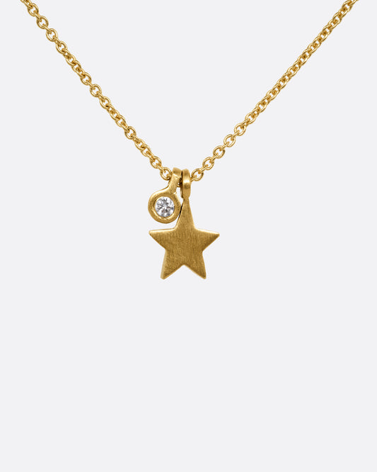 A yellow gold cable chain necklace with a tiny diamond tag and star charm. Shown from the front.