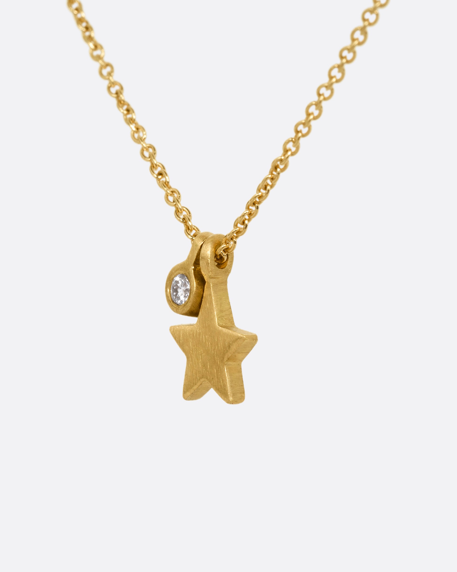 A yellow gold cable chain necklace with a tiny diamond tag and star charm. Shown from the side.