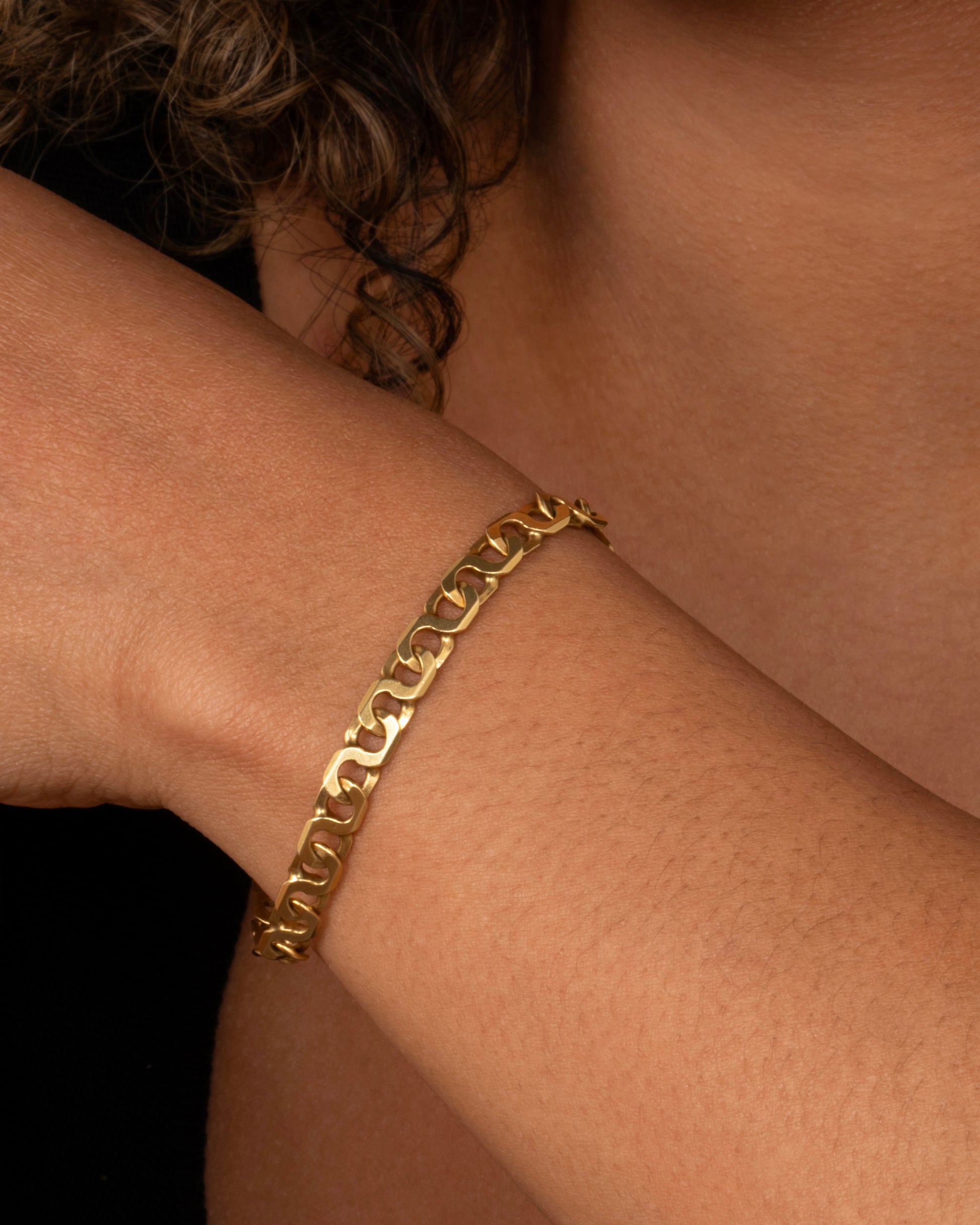 A yellow gold bracelet with infinity links Shown worn on a wrist.