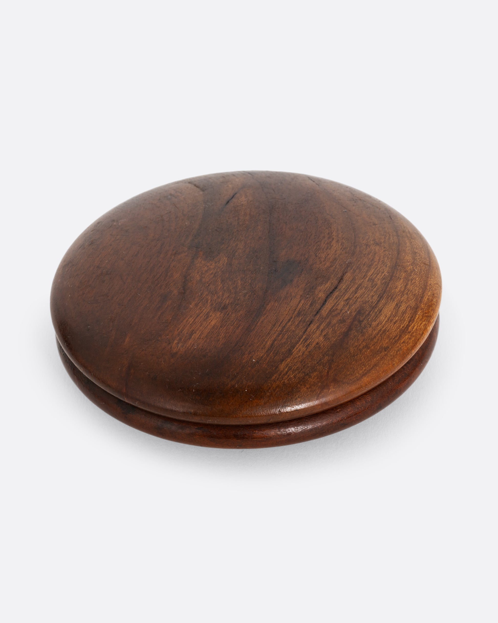 A round wooden snuff box shown closed from the top.