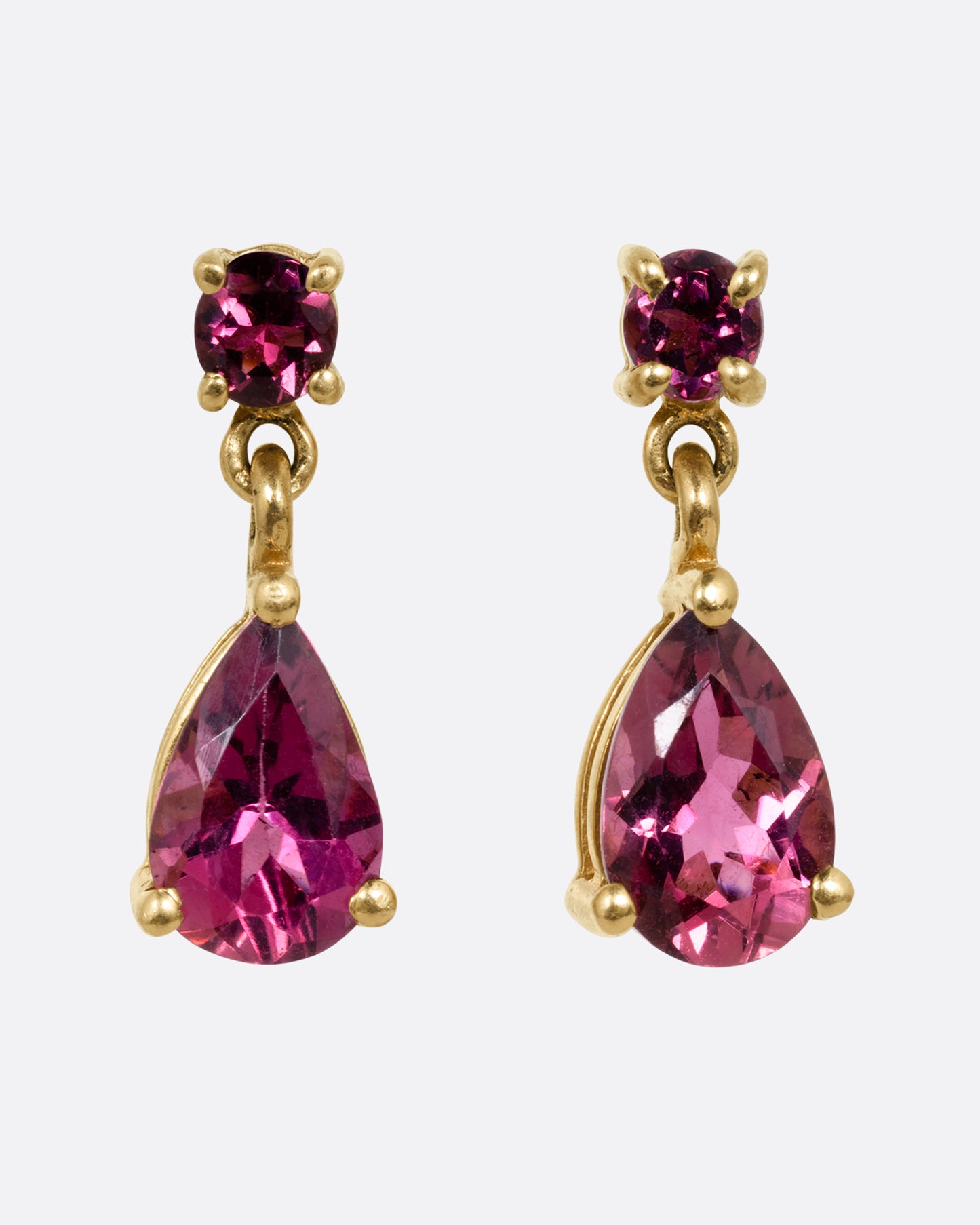 Yellow gold earrings with round prong set pink tourmalines at the top and teardrop shaped pink tourmalines at the bottom. Shown from the front.