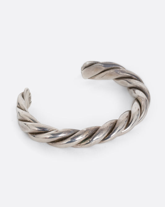 A cuff bracelet with thick, twisted silver strands. Shown at an angle from the front. 