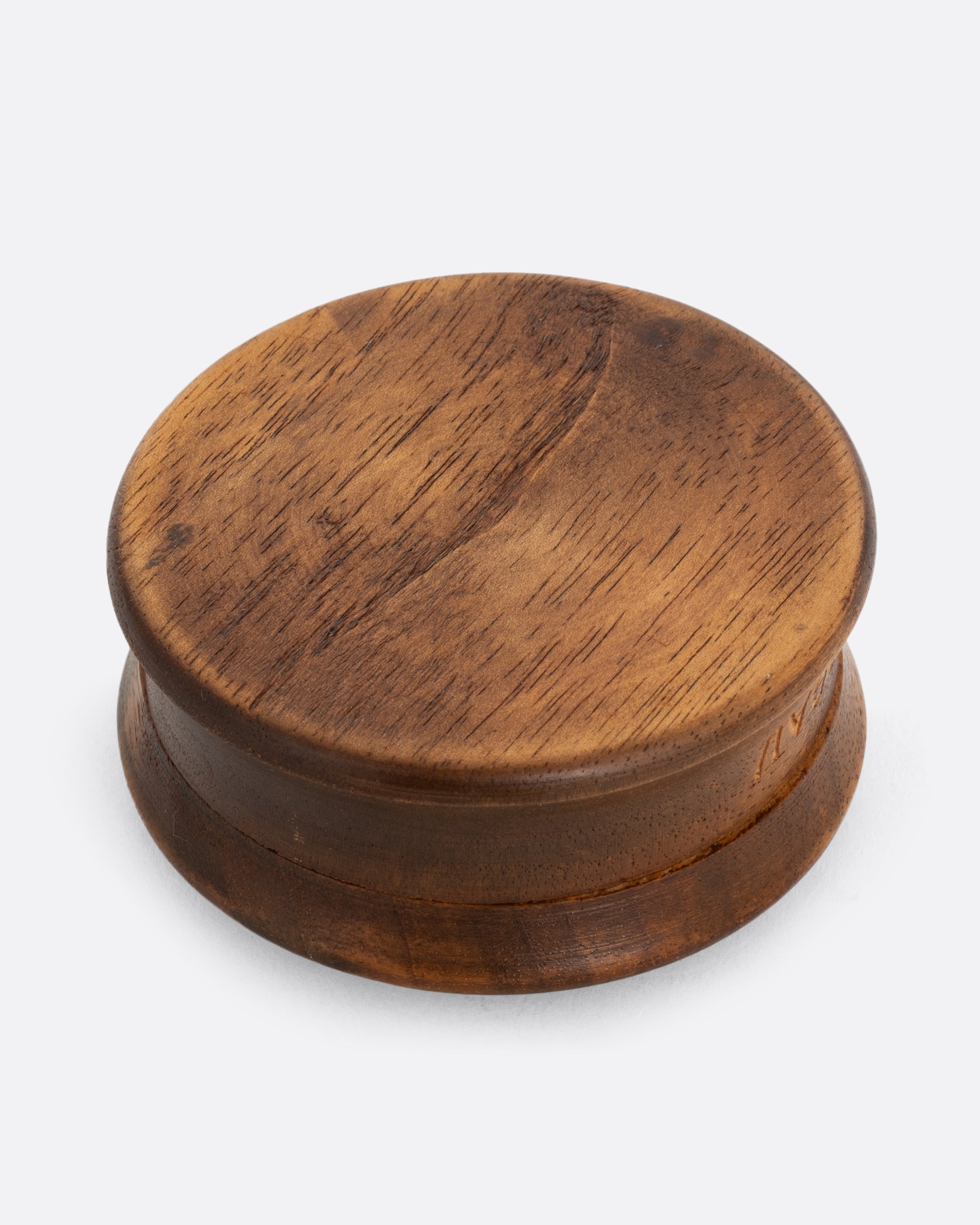 A circular hand carved wooden box with 'Oberammergau', a town in Germany, around its base and a flower on its top. Shown from the bottom.