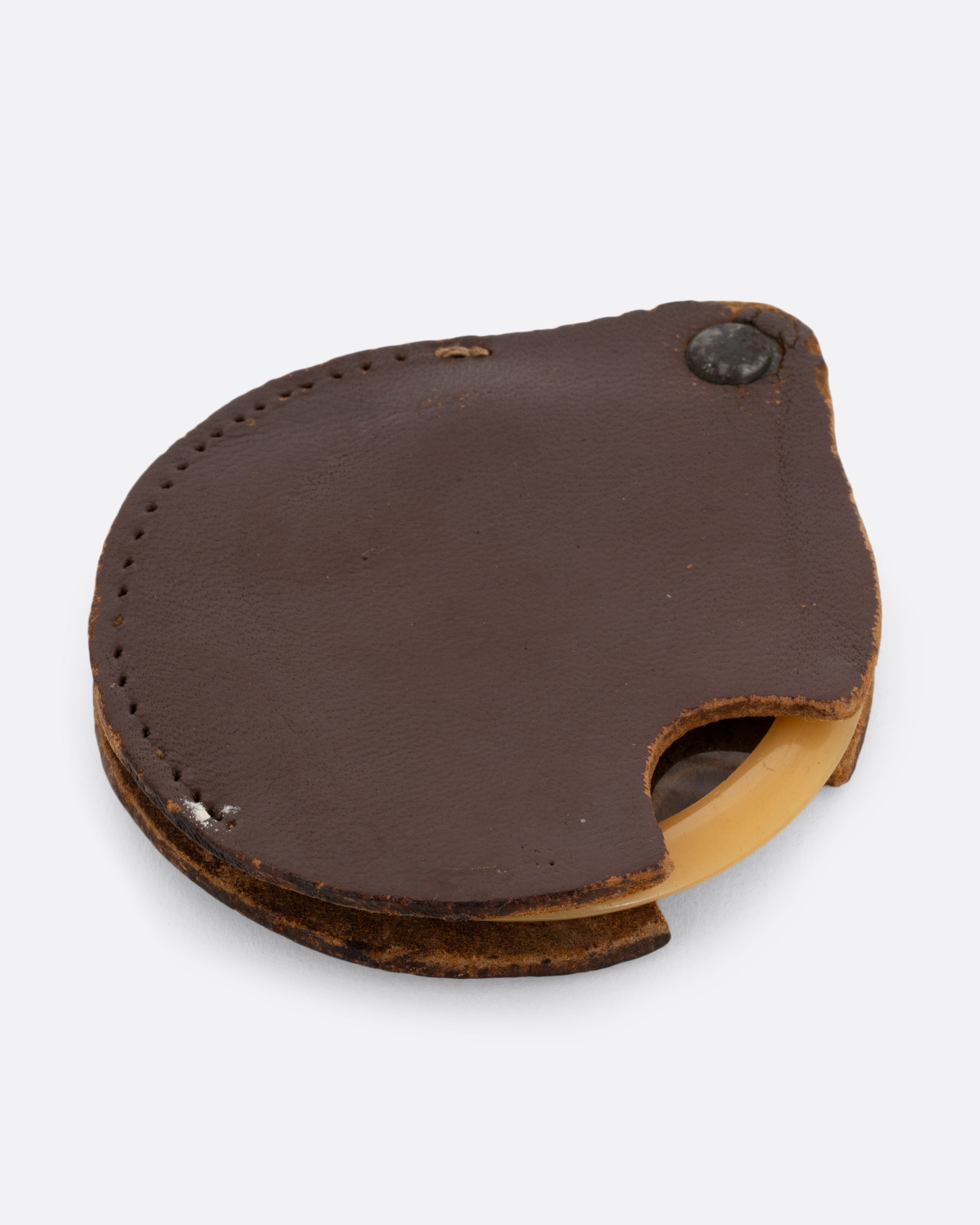 A plastic circular magnifying lens with a yellow edge. The lens slides out from a circular leather case. Shown closed from the front.