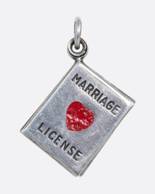 A silver marriage license charm with a red heart on the front. 