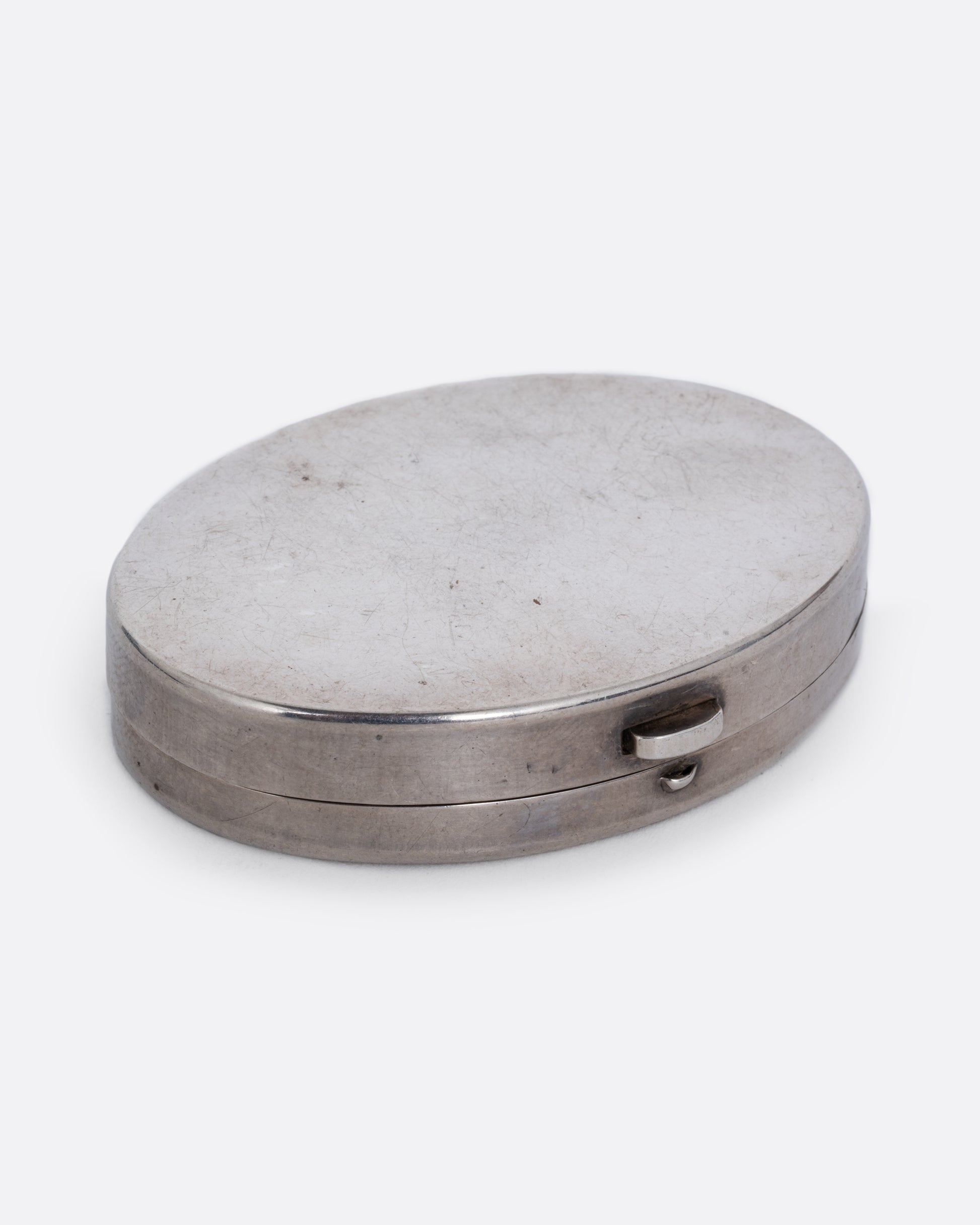 A silver mirror compact shown closed at an angle from the front.