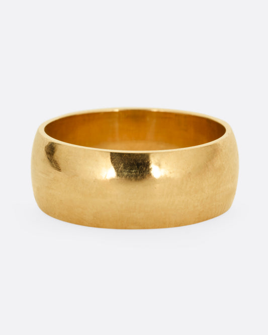 A broad yellow gold band with a rounded silhouette. Shown from the front. 