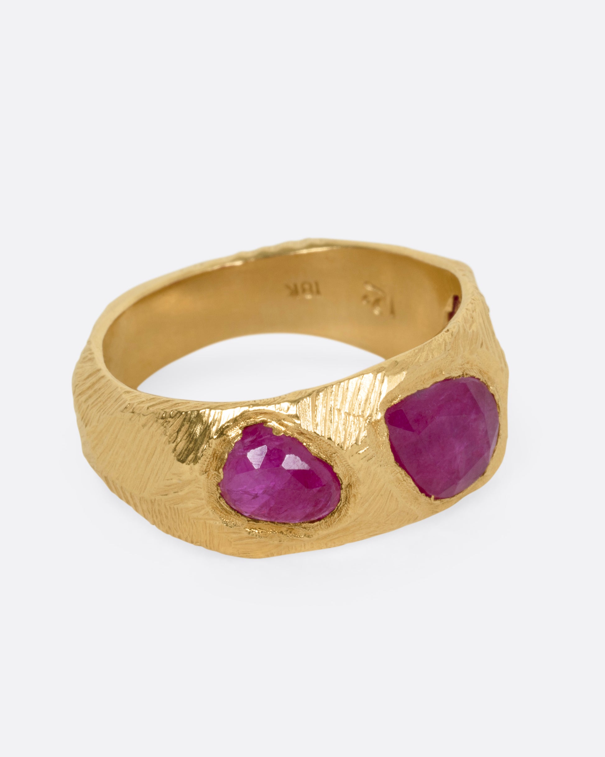 A yellow gold ring with three rubies, shown from the side.