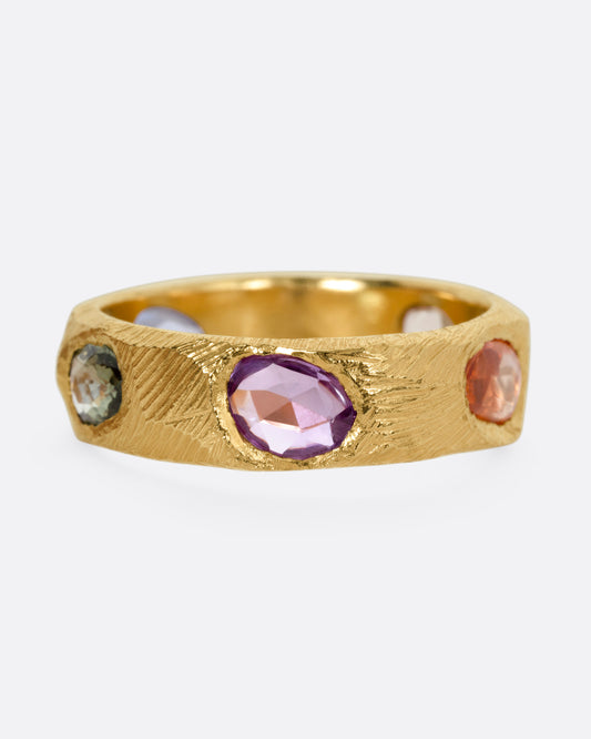 A yellow gold ring with multicolored rose cut sapphires, shown from the front.