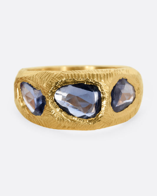 A yellow gold ring with three blue sapphires, shown from the front.