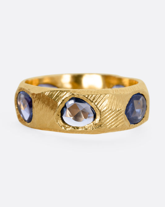 A yellow gold ring with five blue sapphires, shown from the front.