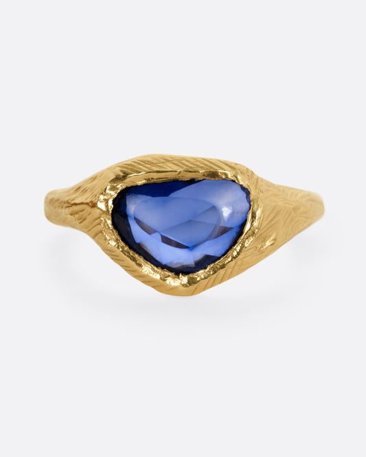 A yellow gold ring with a blue sapphire, shown from the front.