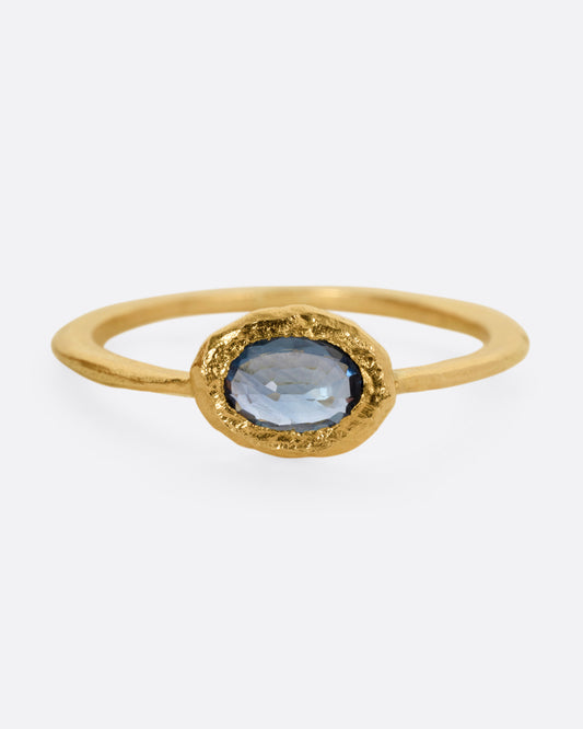 A yellow gold ring with a blue sapphire, shown from the front.