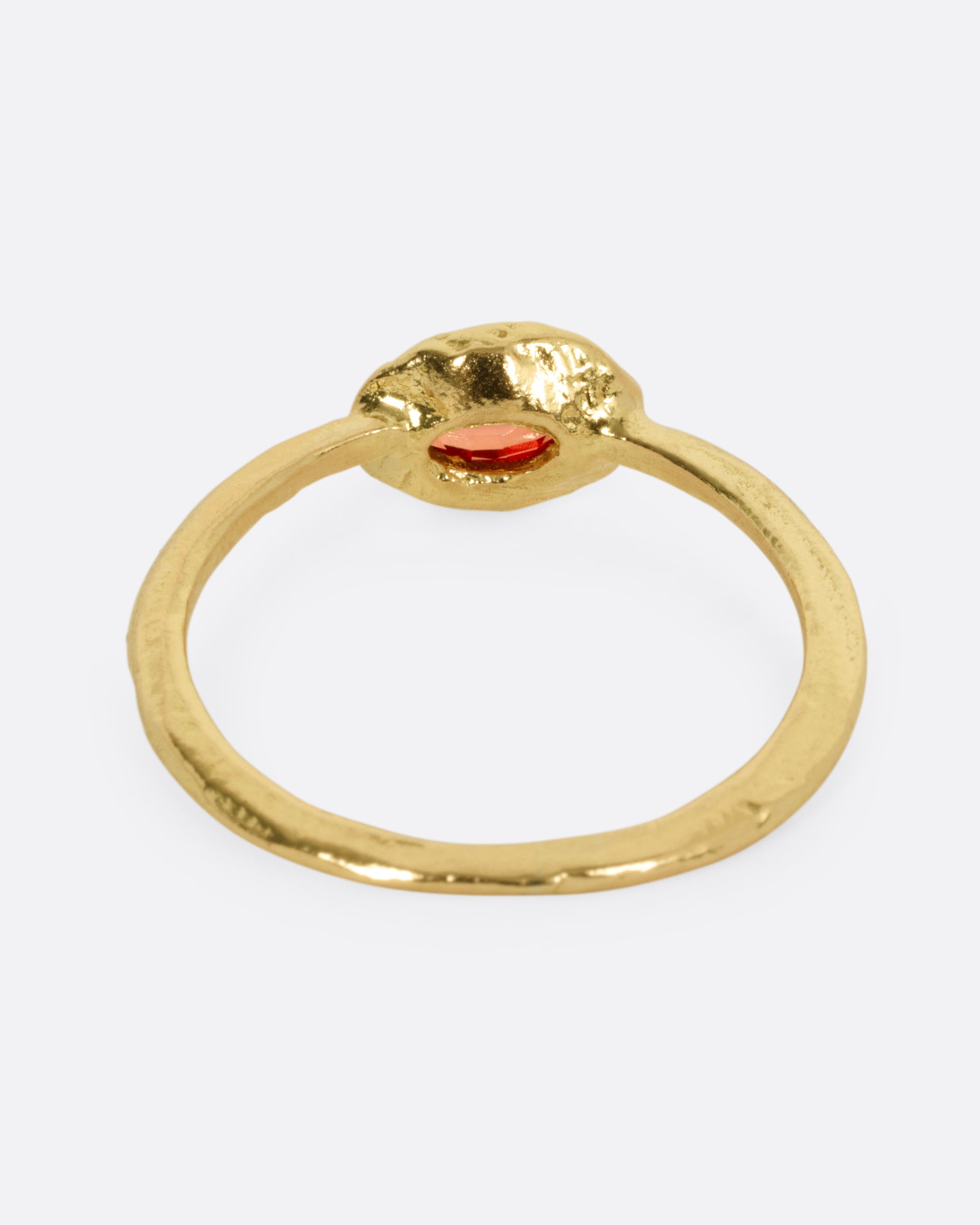 A yellow gold ring with a red sapphire, shown from the back.
