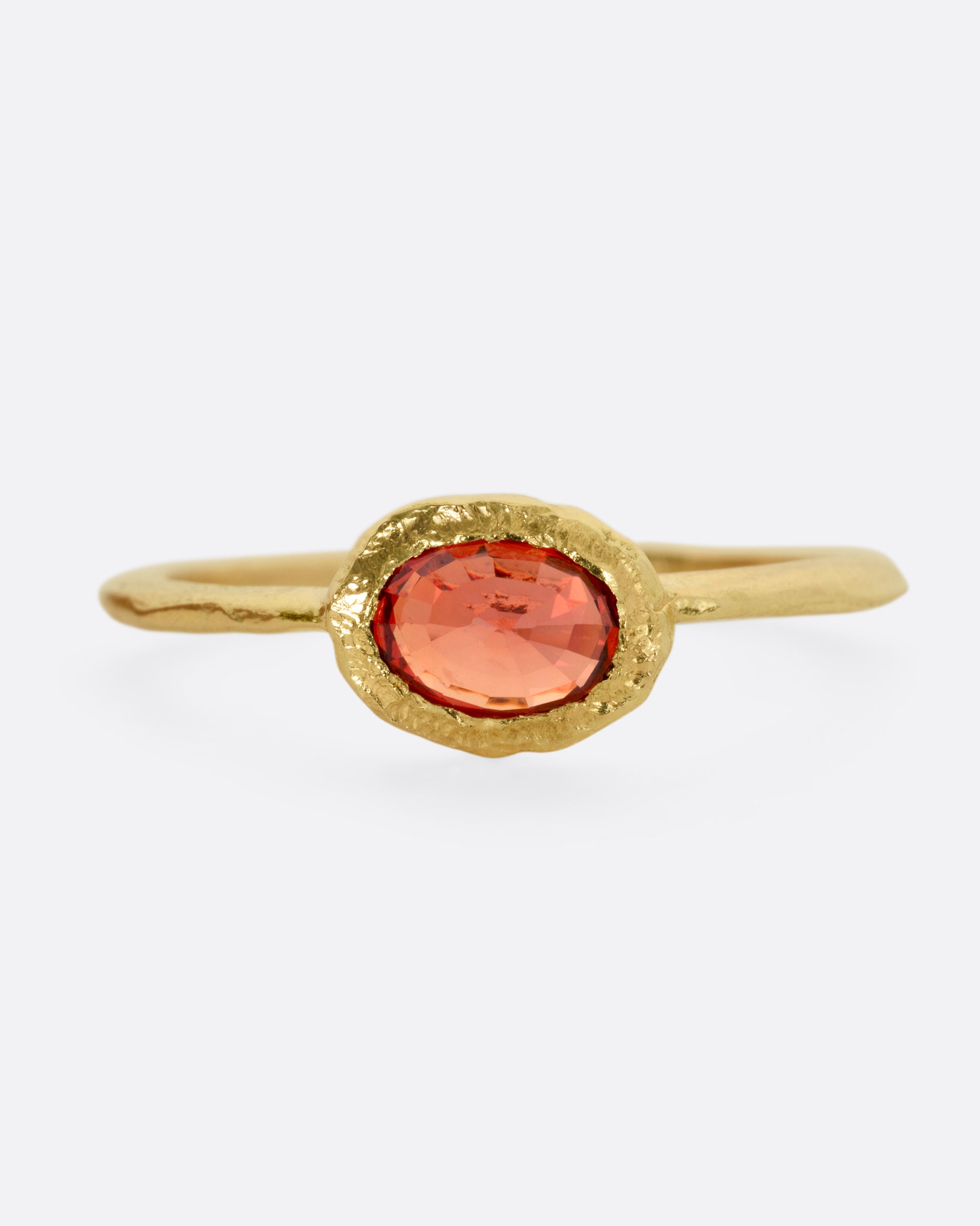 A yellow gold ring with a red sapphire, shown from the front.