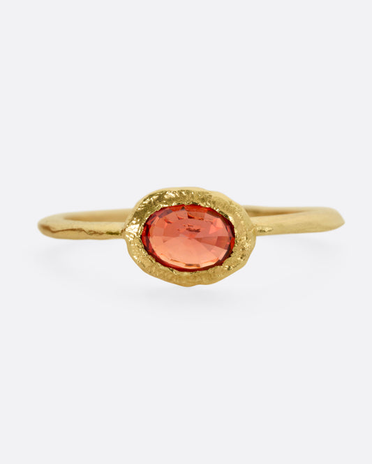 A yellow gold ring with a red sapphire, shown from the front.