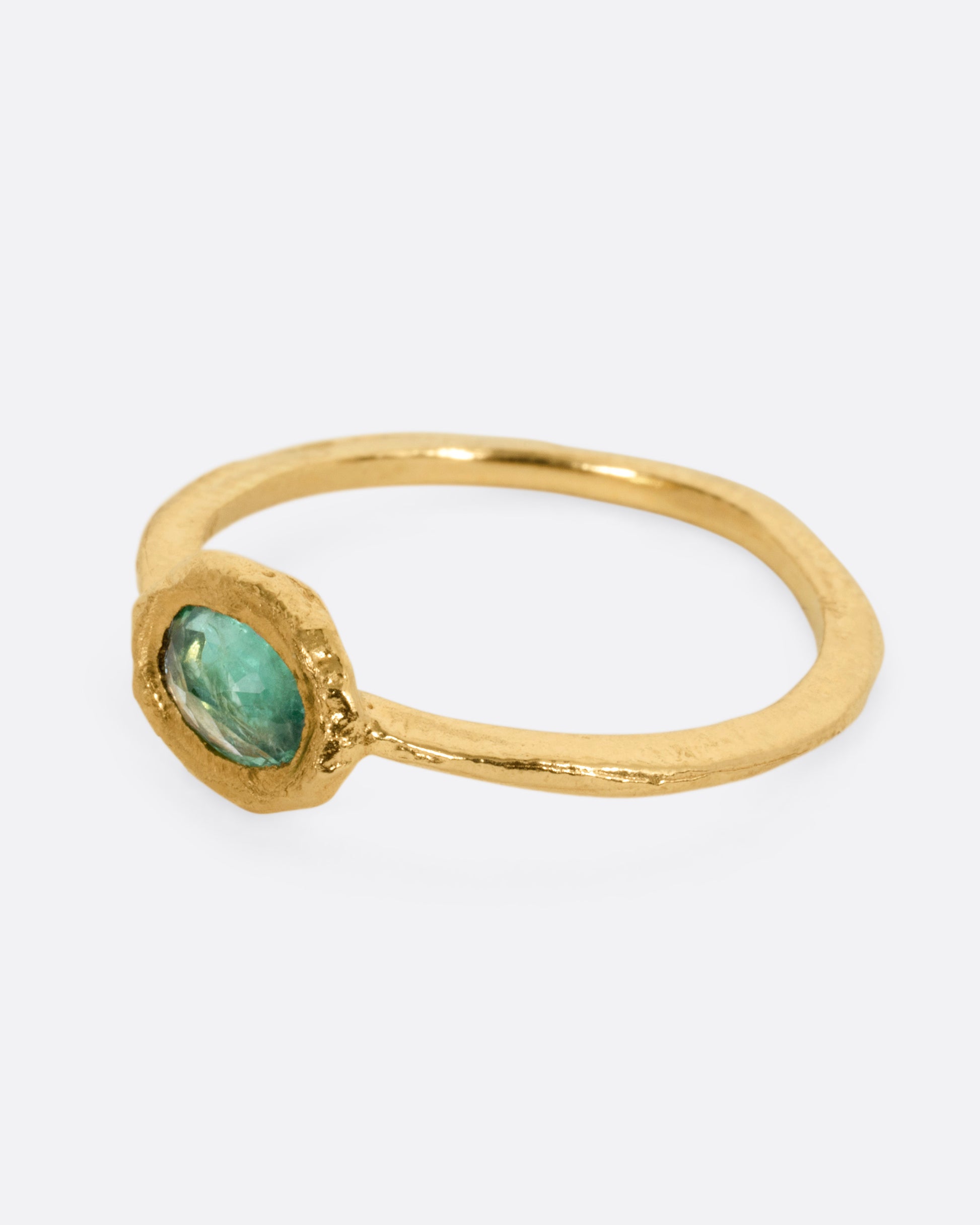 A yellow gold ring with an oval emerald, shown from the side.