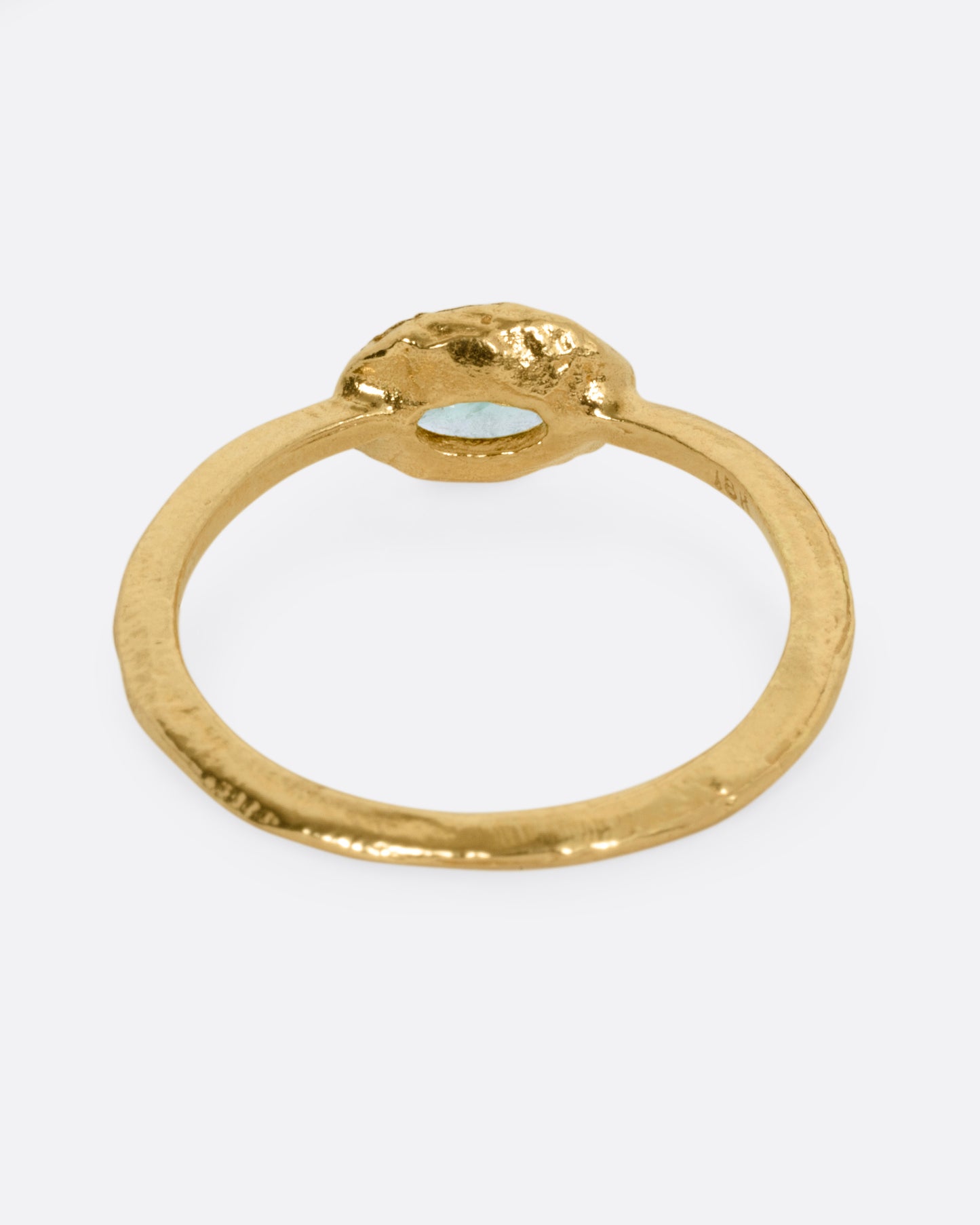A yellow gold ring with an oval emerald, shown from the back.