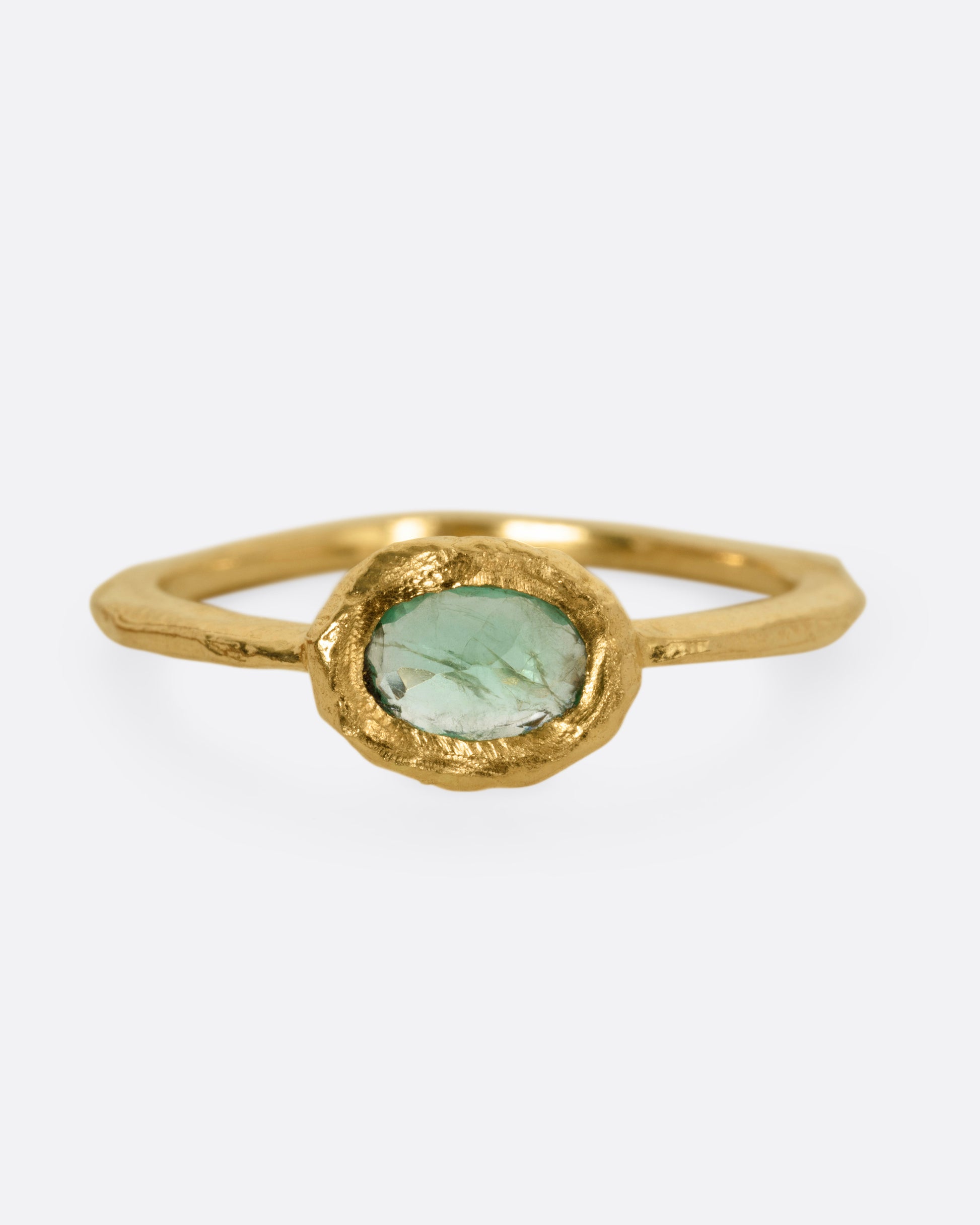 A yellow gold ring with an oval emerald, shown from the front.