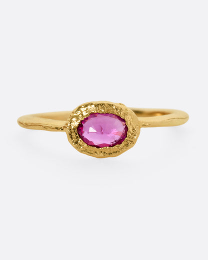 A yellow gold ring with an oval ruby, shown from the front.