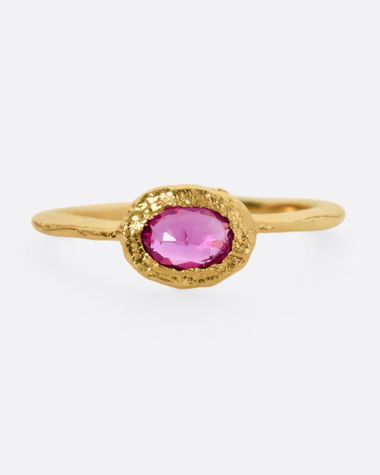 A yellow gold ring with an oval ruby, shown from the front.