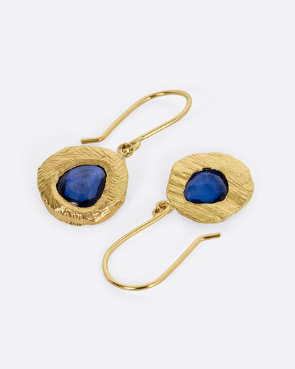 A pair of yellow gold drop earrings with blue sapphires. One earring is shown from the front, the other from the back.