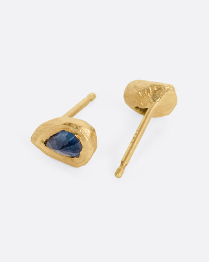 Yellow gold blue sapphire teardrop stud earrings, the pair laid flat showing the posts