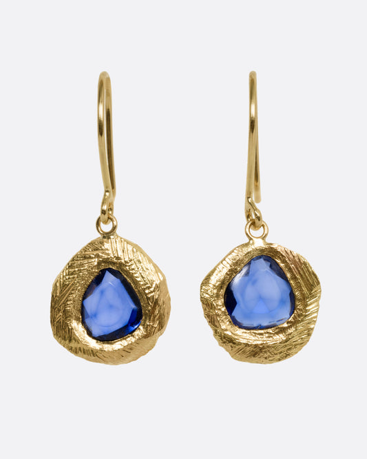 A pair of yellow gold drop earrings with blue sapphires, shown from the front.
