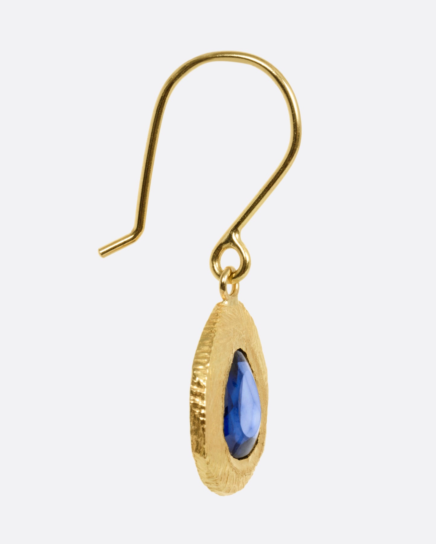 A yellow gold drop earring with a blue sapphire, shown from the side.