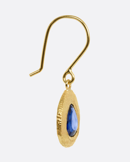 A yellow gold drop earring with a blue sapphire, shown from the side.
